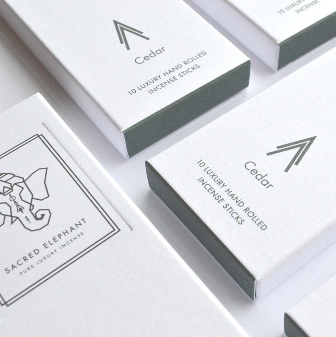 Minimalistische Nahaufnahme der Sacred Elephant Cedar Räucherstäbchen – elegante weiße Verpackung mit graugrünem Etikett und dezentem Logo.