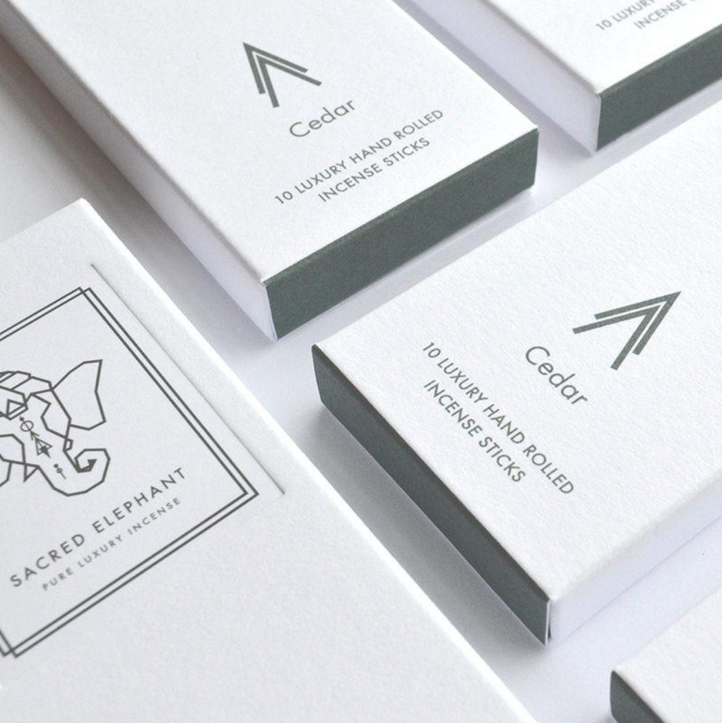 Minimalistische Nahaufnahme der Sacred Elephant Cedar Räucherstäbchen – elegante weiße Verpackung mit graugrünem Etikett und dezentem Logo.