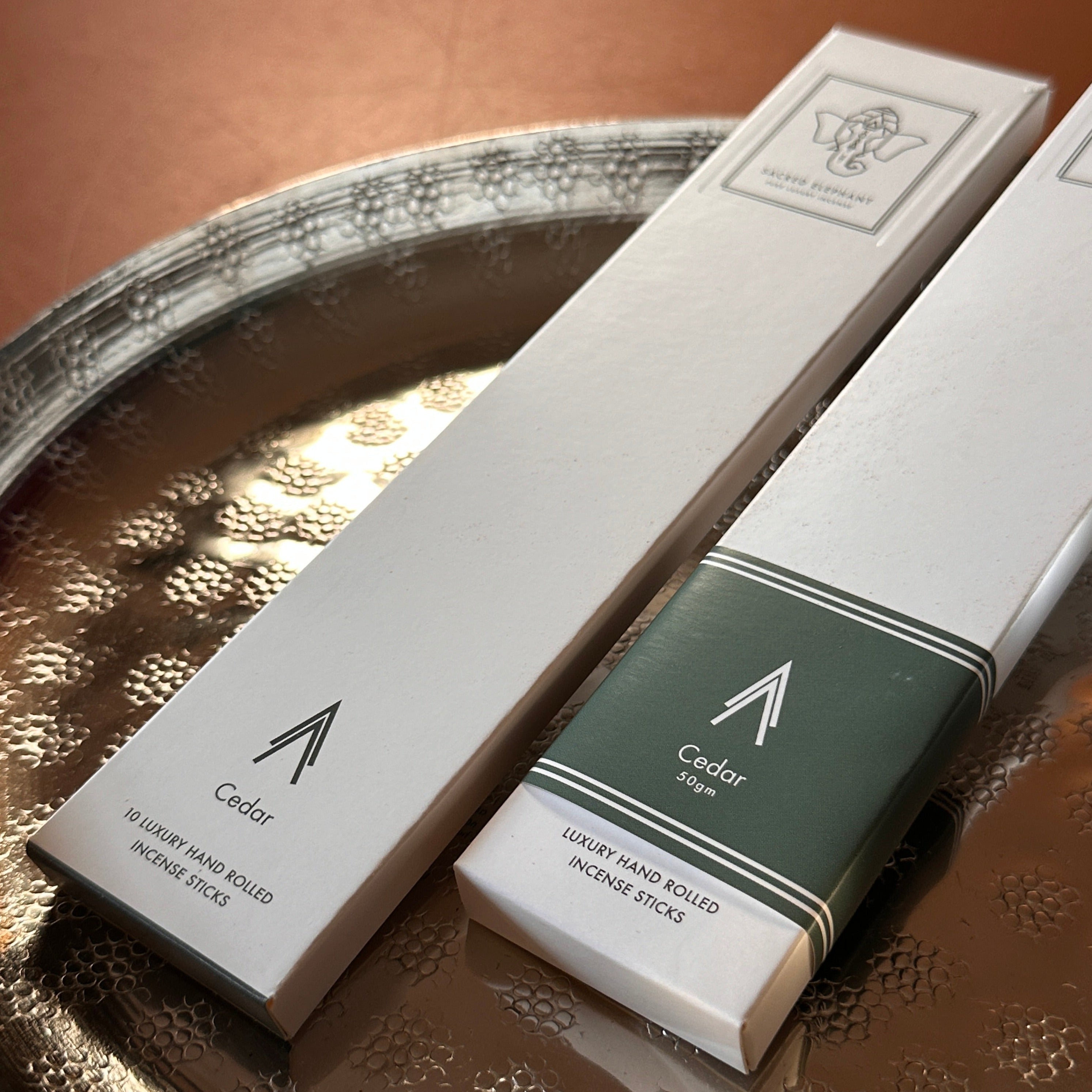 Sacred Elephant Cedar Räucherstäbchen im Set – klassische Packung in edlem Design auf silbernem Tablett mit harmonischem Farbspiel.