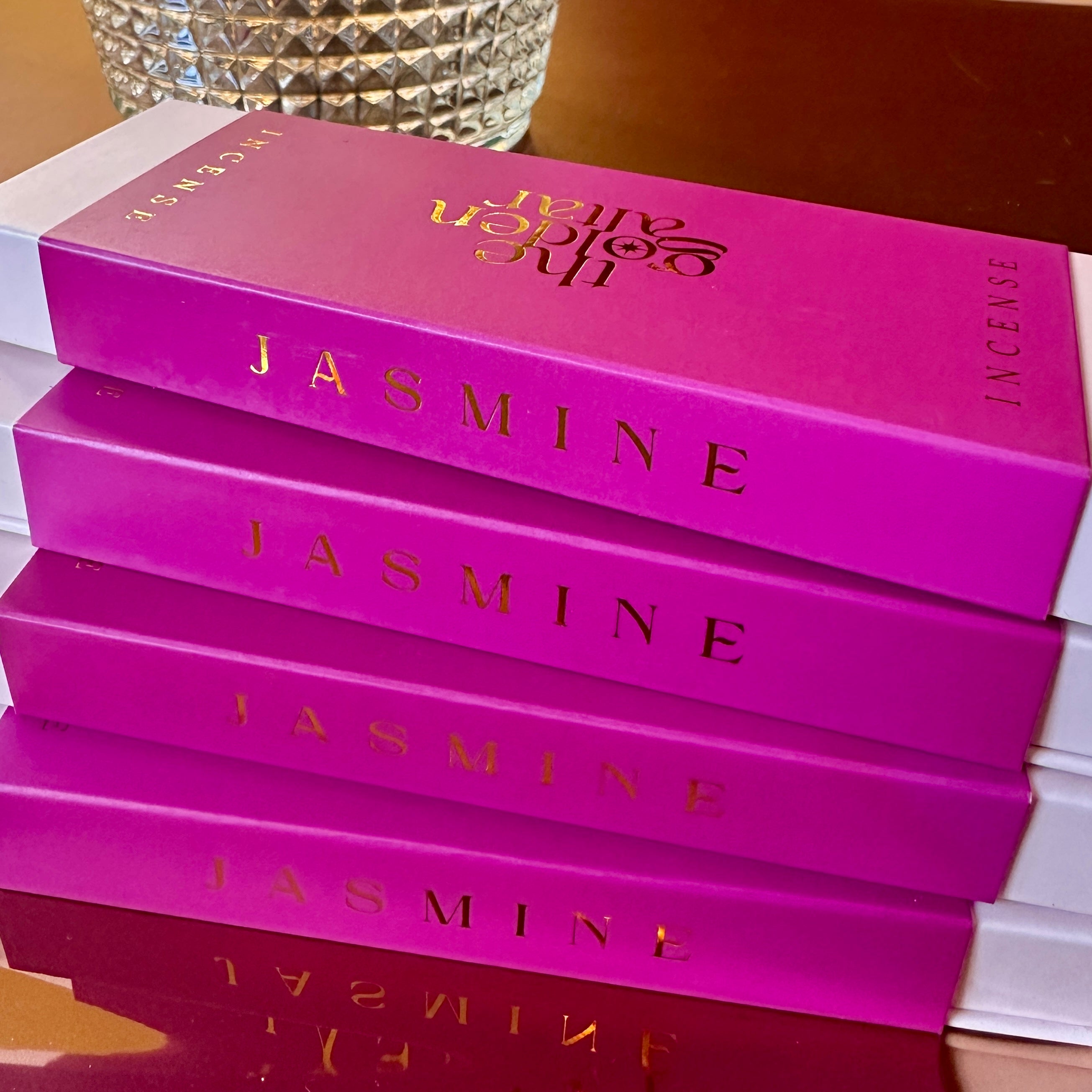 Gestapelte The Golden Altar Jasmine Räucherstäbchen – glänzende pinke Boxen mit goldener Schrift, luxuriös und modern.