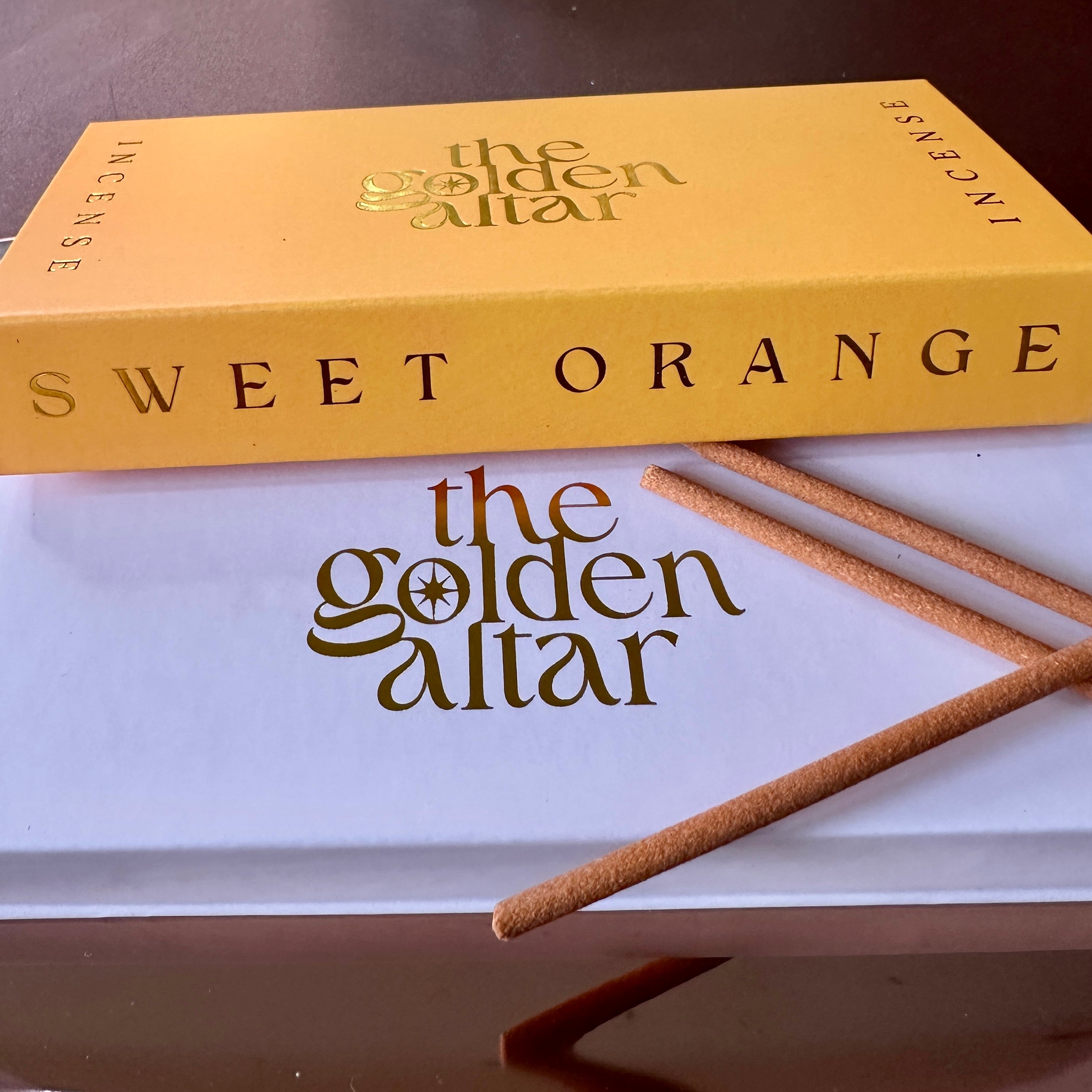 The Golden Altar Sweet Orange Räucherstäbchen – sonniger Duft mit goldener Verpackung auf weißem Untergrund, luxuriös und warm.